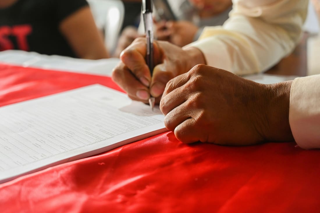 Hand signing a form with columns of amounts