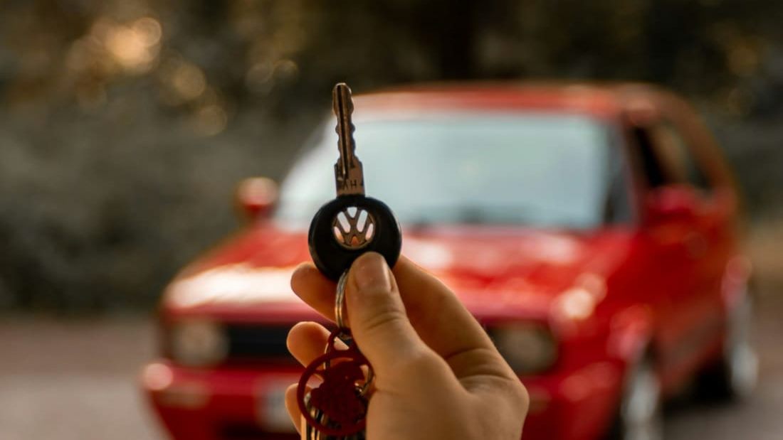 Key to a red used car held in hand